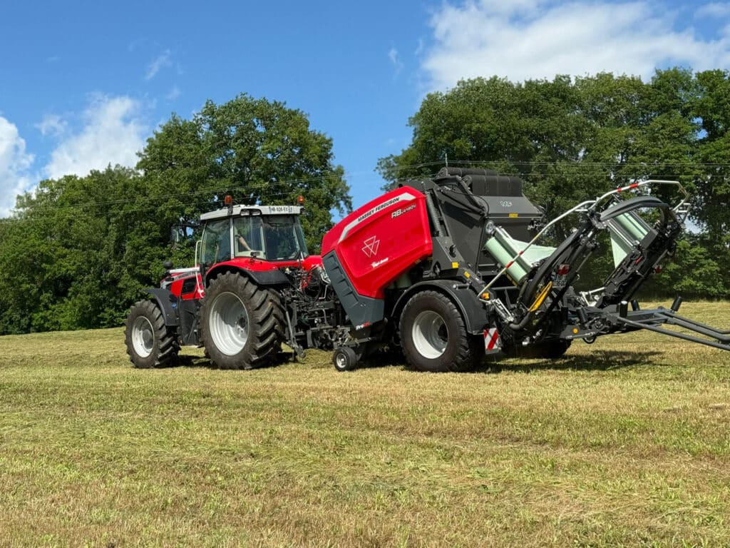 Tracteur Massey Ferguson rouge et gris tirant une presse-enrubanneuse Massey Ferguson RB 4160V en train de presser l'herbe coupée sous un ciel bleu.